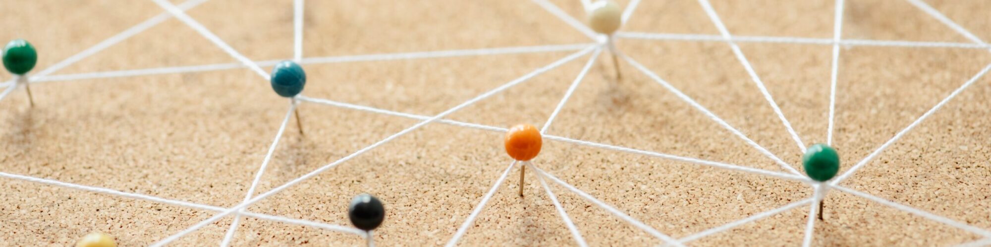 Colocation - Points of Presence Colorful pins connected by string on a corkboard. Pins and strings form a network. Pins and strings illustrate connections. Pins and strings concept. Connection background, business network background