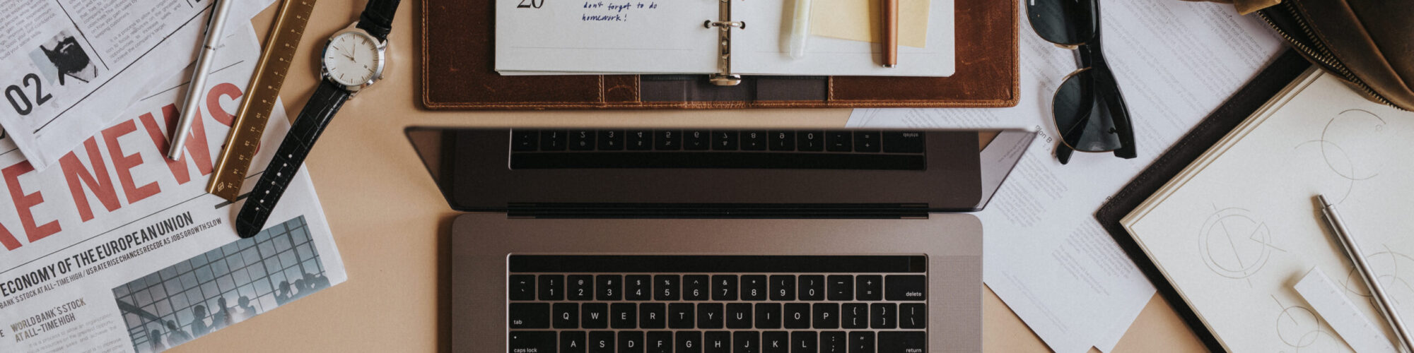 Digital laptop on a table with notebook and newspapers