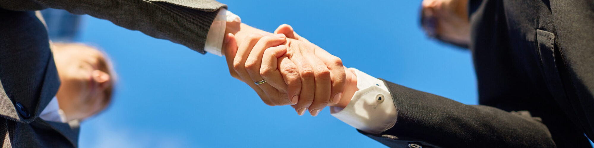 Handshake of partners and blue sky above